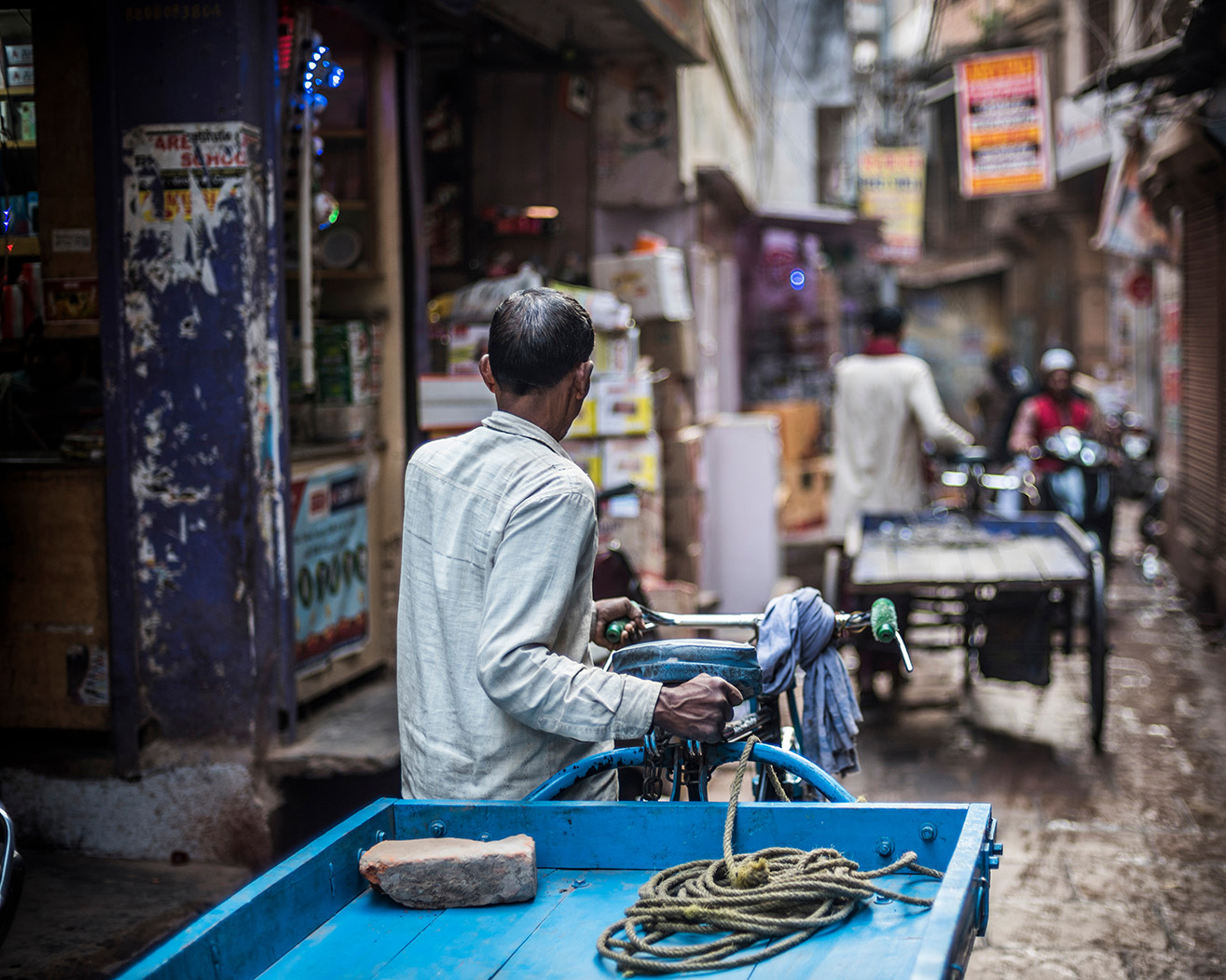 Man pulling blue cart in Varanasi streets